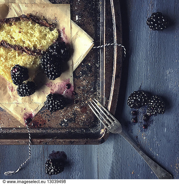 Overhead view of blackberries and dessert with wax papers in tray on table