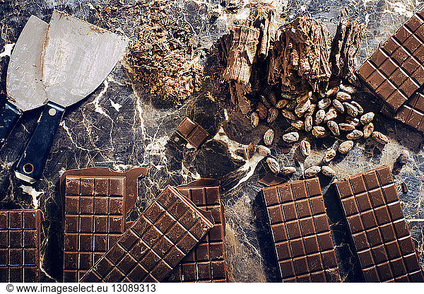 Overhead view of chocolate bars with nuts and kitchen knife on table
