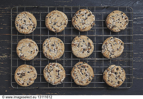 Overhead view of chocolate chip cookies on cooking rack over wooden table