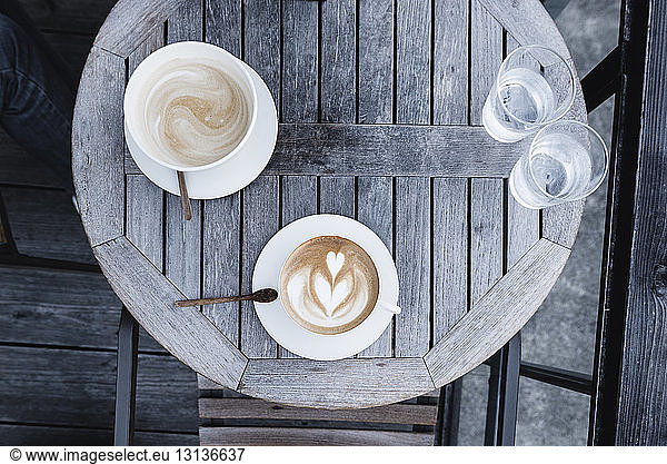 Overhead view of coffee cups and water glasses on wooden table
