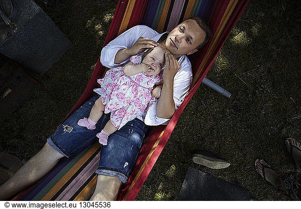 Overhead view of father with daughter relaxing in hammock