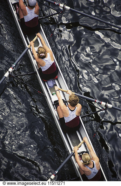 Overhead view of female crew racers rowing scull boat.