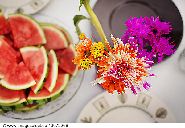 Overhead view of flower vase with watermelons on table