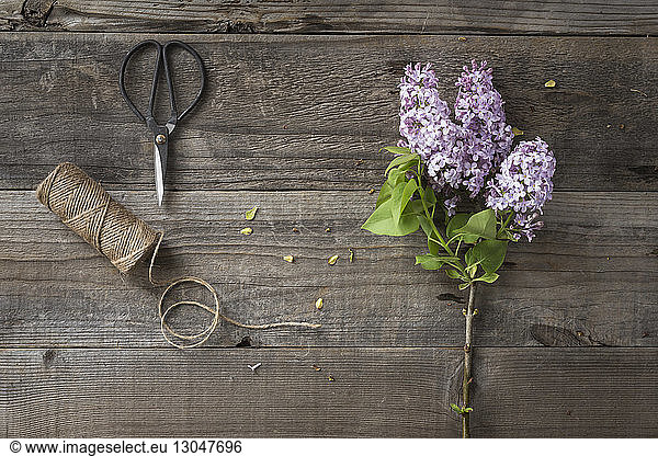 Overhead view of flowers with string and scissors on wooden table