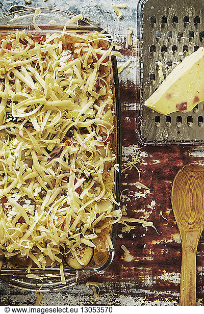 Overhead view of food in serving dish by cheese grater on table