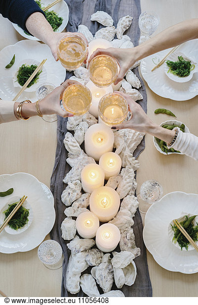 Overhead view of four people sharing a meal  plates of sushi and a table setting for a celebration meal.
