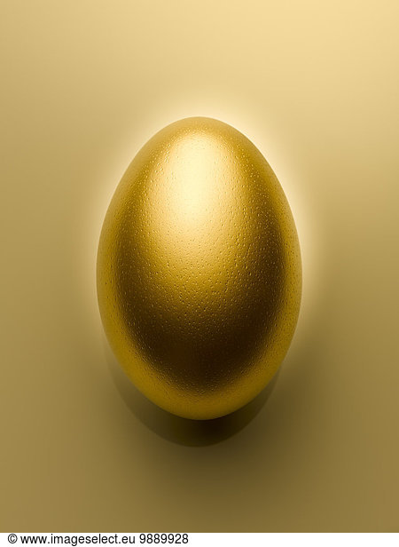 Overhead view of golden egg on gold background still life