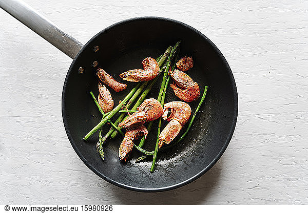 Overhead view of grilled prawns and asparagus on frying pan
