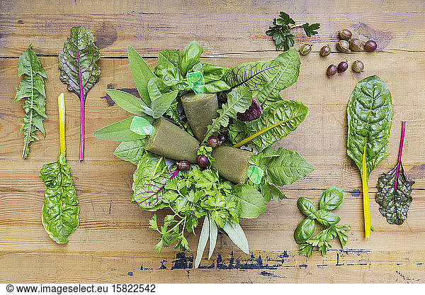 Overhead view of homemade green vegetables and herb popsicles on wooden table