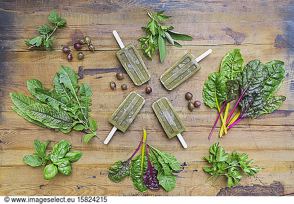 Overhead view of homemade green vegetables and herb popsicles on wooden table
