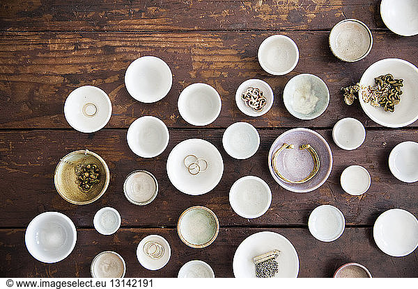 Overhead view of jewelry in bowls and plates arranged on table
