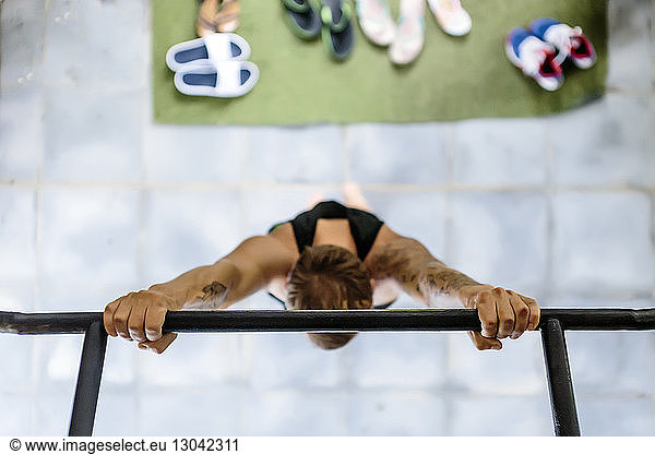 Overhead view of man hanging on gymnastics bar at gym