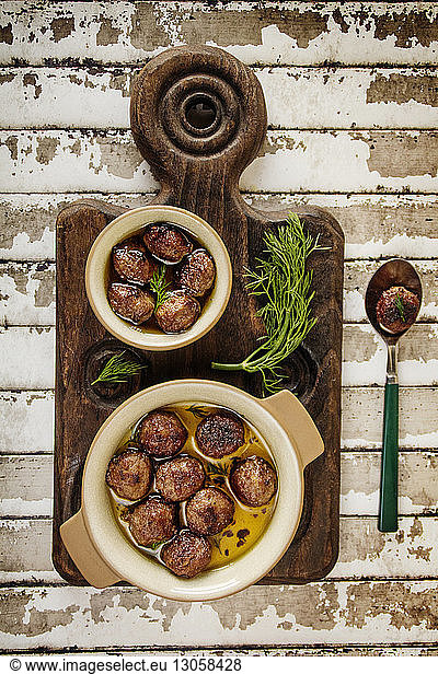Overhead view of meatballs in bowls on cutting board