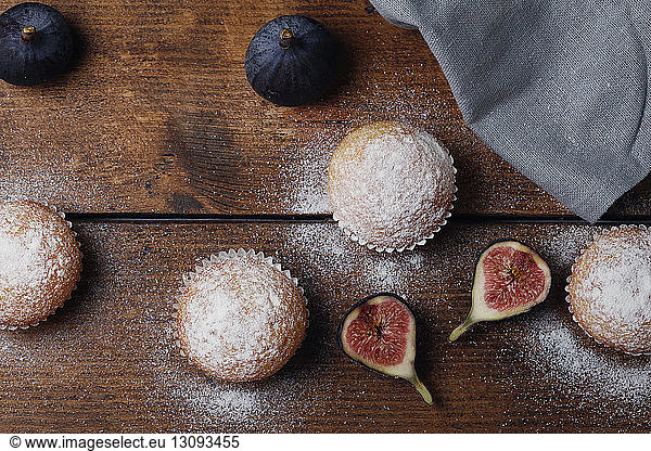 Overhead view of muffins with figs by napkin on wooden table