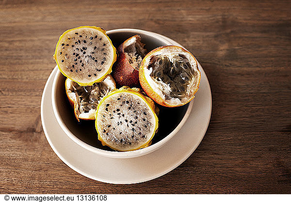 Overhead view of passion fruit and dragon fruit slices in bowl on wooden table