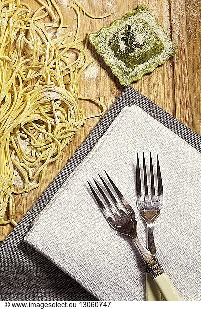 Overhead view of pasta and ravioli with forks on table