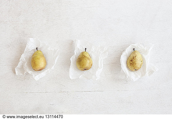 Overhead view of pears in wax papers arranged on wooden table