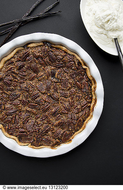 Overhead view of pecan pie by cream on table
