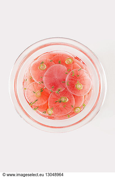 Overhead view of radishes in bowl on white background