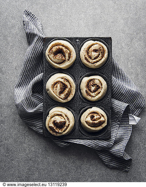 Overhead view of raw cinnamon rolls in baking tray on napkin