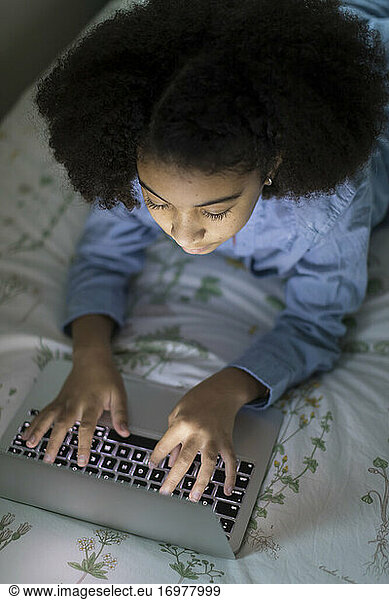 Overhead view of ten year-old bi-racial girl working on laptop