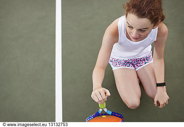 Overhead view of tennis player with tennis racket crouching on tennis court