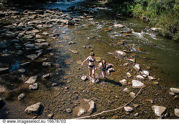 Overhead view of two sisters walking through a shallow creek