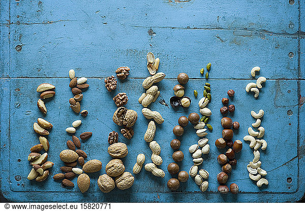 Overhead view of various nuts on blue rustic table