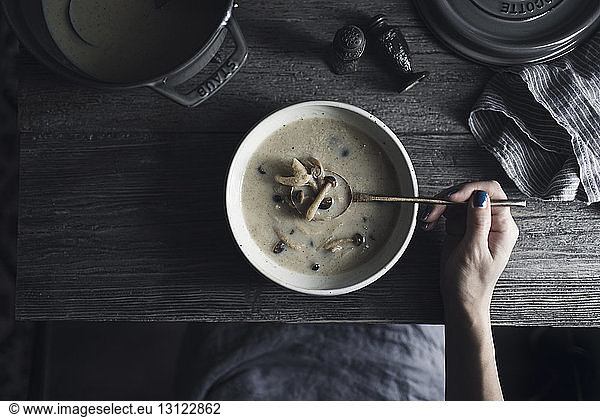Overhead view of woman having shimeji mushroom soup at wooden table