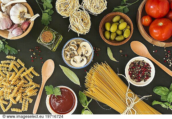 Overhead view raw pasta with ingredients black background