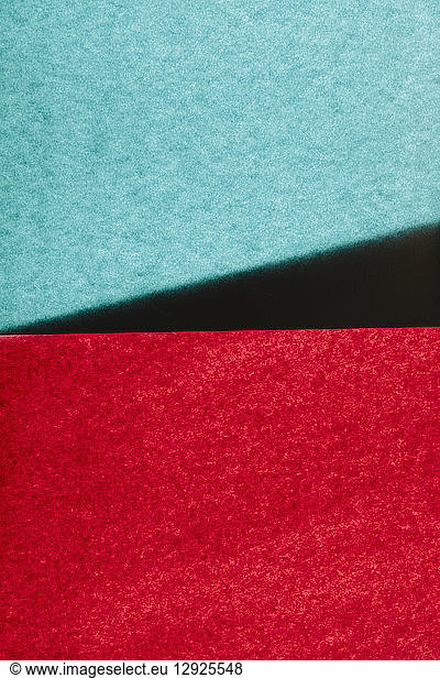Overlapping pieces of multi-coloured construction paper on illuminated backdrop.