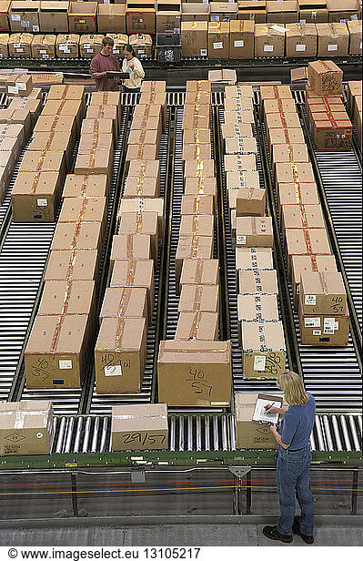 Overview of a large industrial distribution warehouse storing products in cardboard boxes on conveyor belts and racks.