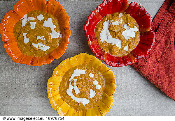 overview of colorful ceramic bowls of winter squash soup with napkin