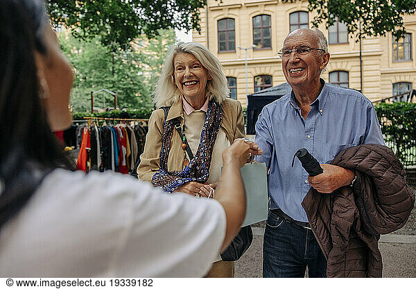 Owner giving shopping bag to senior customers at market