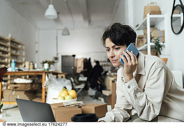Owner talking on phone and working at ceramics workshop