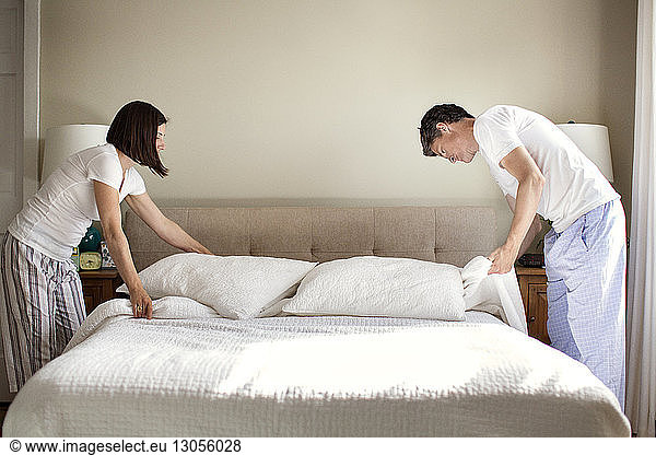 Paar arrangiert Bett zu Hause