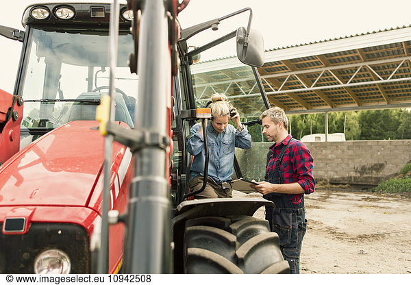 Paar bespricht Dokument mit dem Traktor auf dem Bauernhof