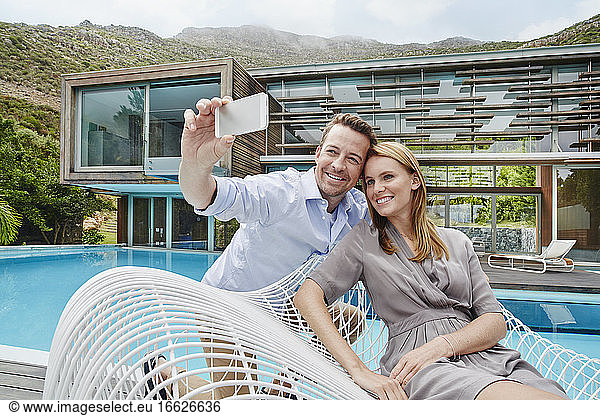 Paar  das ein Selfie mit dem Smartphone macht  während es gegen das Smartphone sitzt