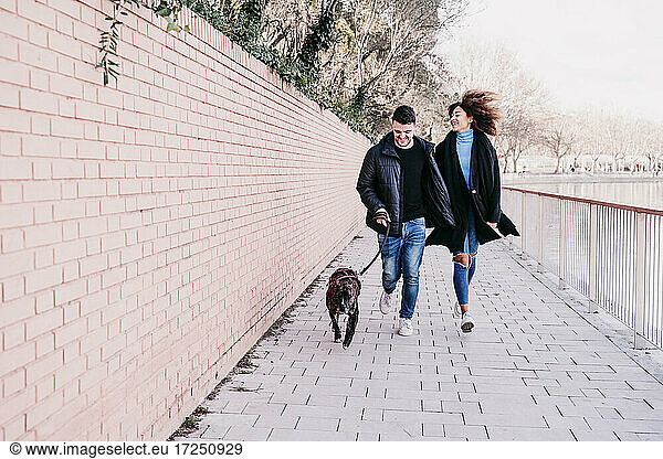 Paar genießt beim Laufen mit Haustier auf dem Fußweg