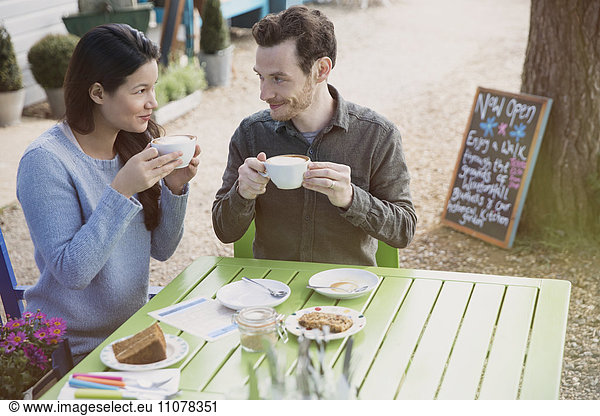 Paar genießt Cappuccinos und Dessert in einem Outdoor-Café