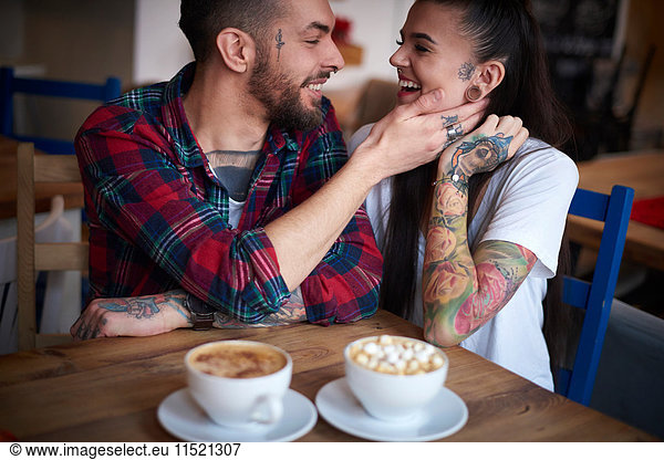 Paar im Café von Angesicht zu Angesicht lächelnd