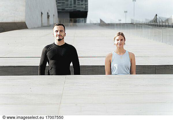 Paar in Sportkleidung steht an einer Stützmauer