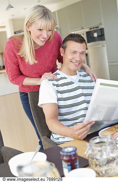 Paar liest Zeitung beim Frühstück