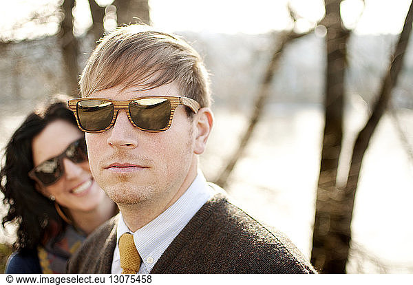 Paar mit Sonnenbrille gegen kahle Bäume