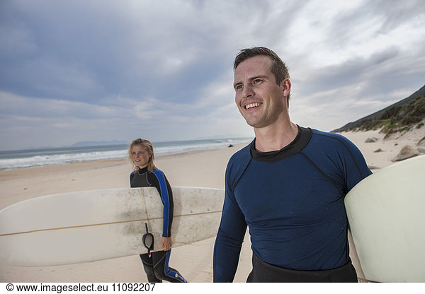 Paar mit Surfbrettern am Strand