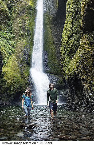 Paar steht im Strom gegen Wasserfall