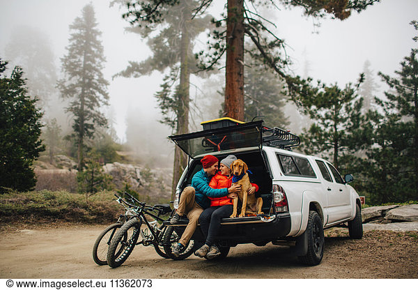 Paar und Hund sitzen auf der Heckklappe eines Jeepwagens  Sequoia National Park  Kalifornien  USA