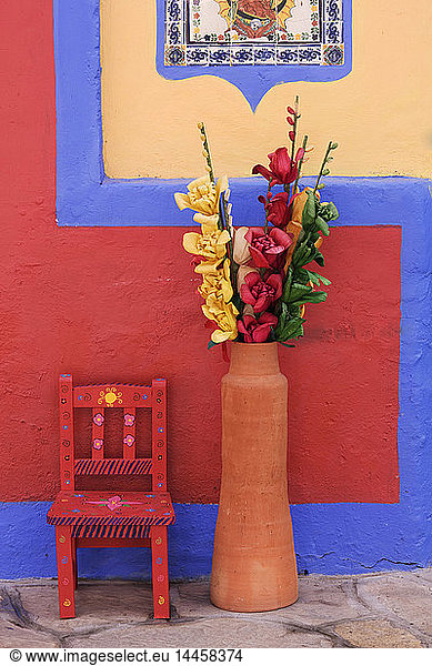 Painted chair next to vase with flowers  Chiapas  Mexico