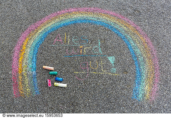Painted rainbow on street with text 'Everything will fall into place'