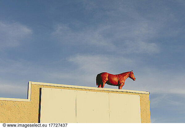Painted red horse on building rooftop